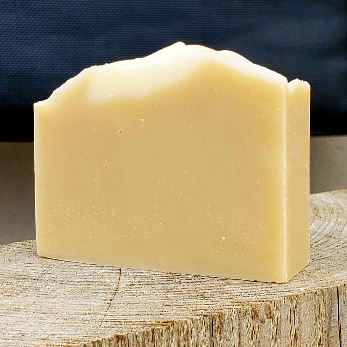 Bar of handmade natural soap on a wooden block with a dark background