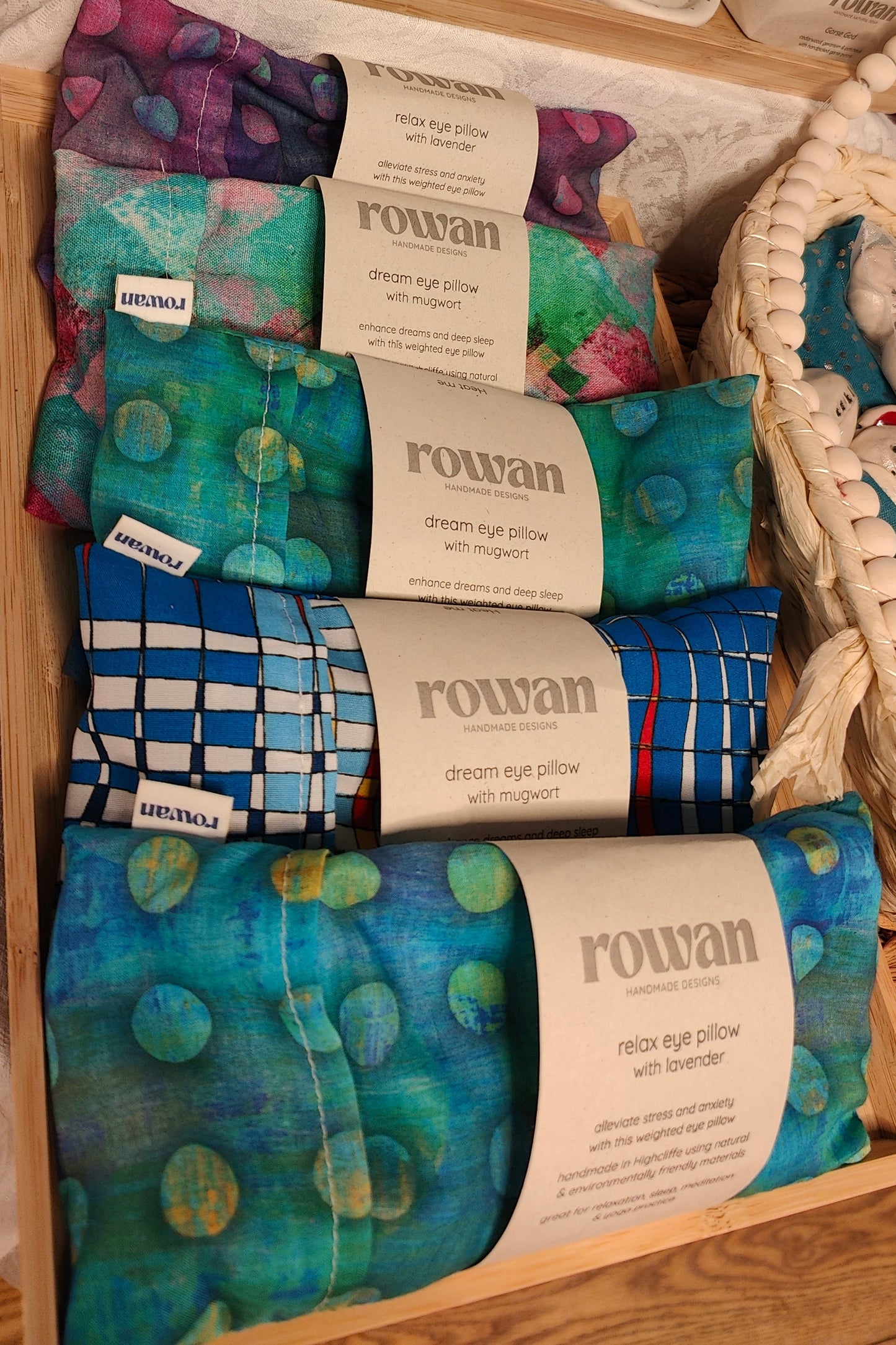 Packaged eye pillows with 'rowan' branding on a wooden surface