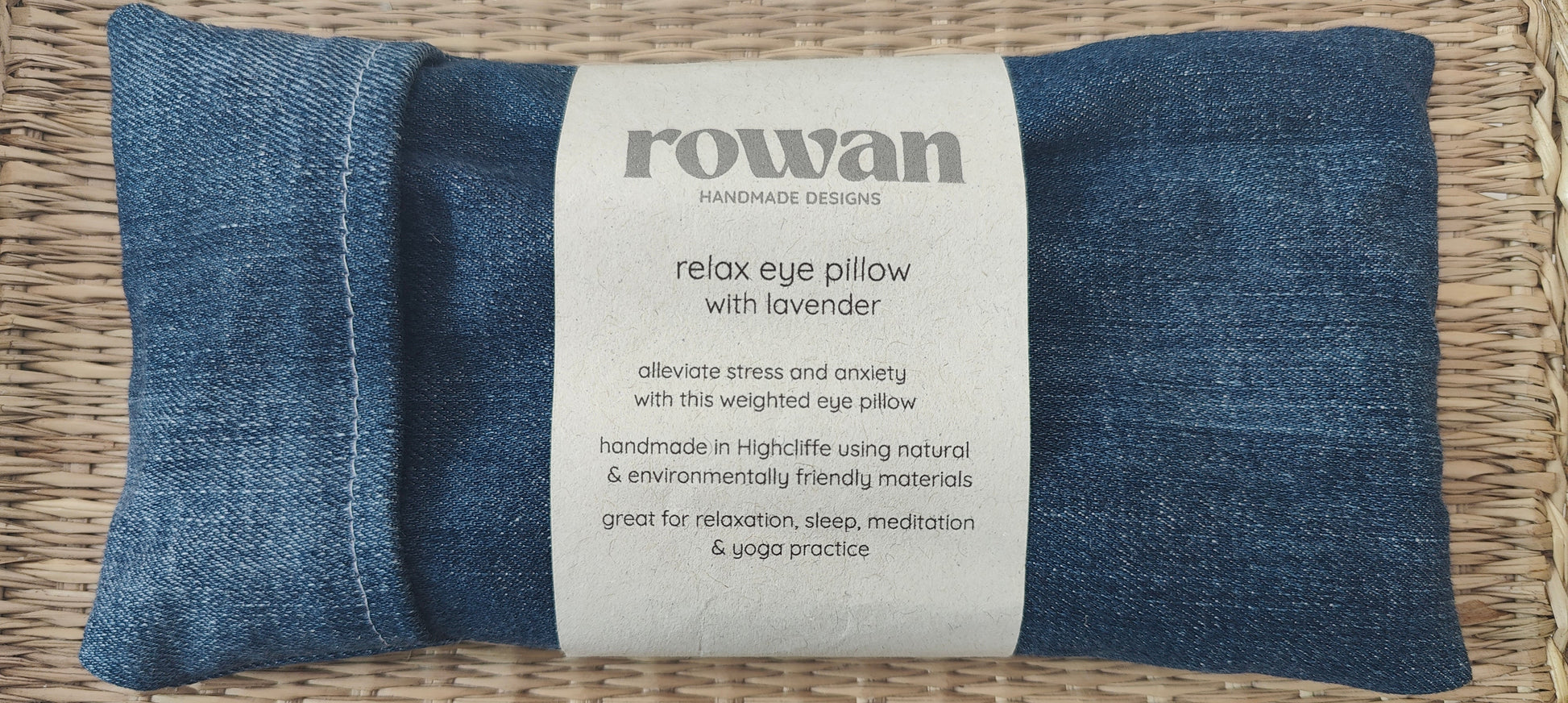 Blue denim eye pillow with a label on a woven surface