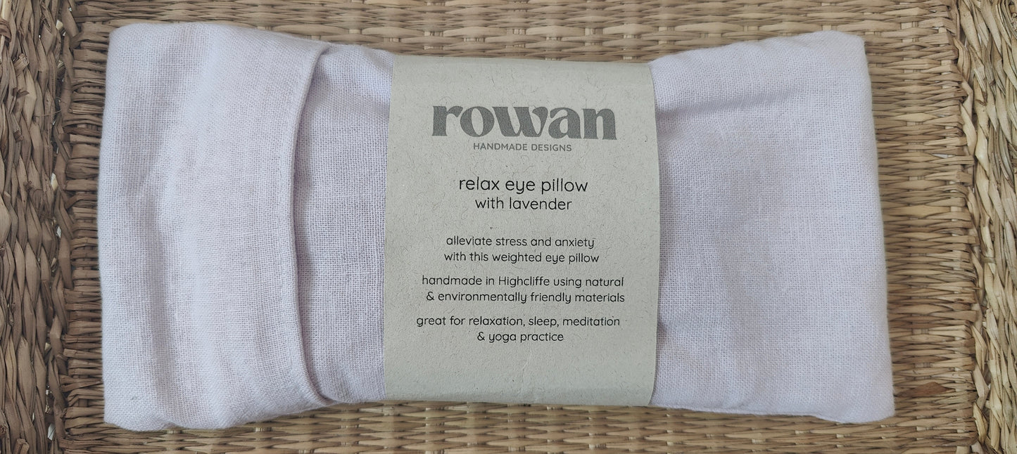 Pale lilac eye pillow with a label on a woven surface